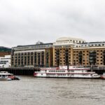 white and red boat on water near brown concrete building during daytime