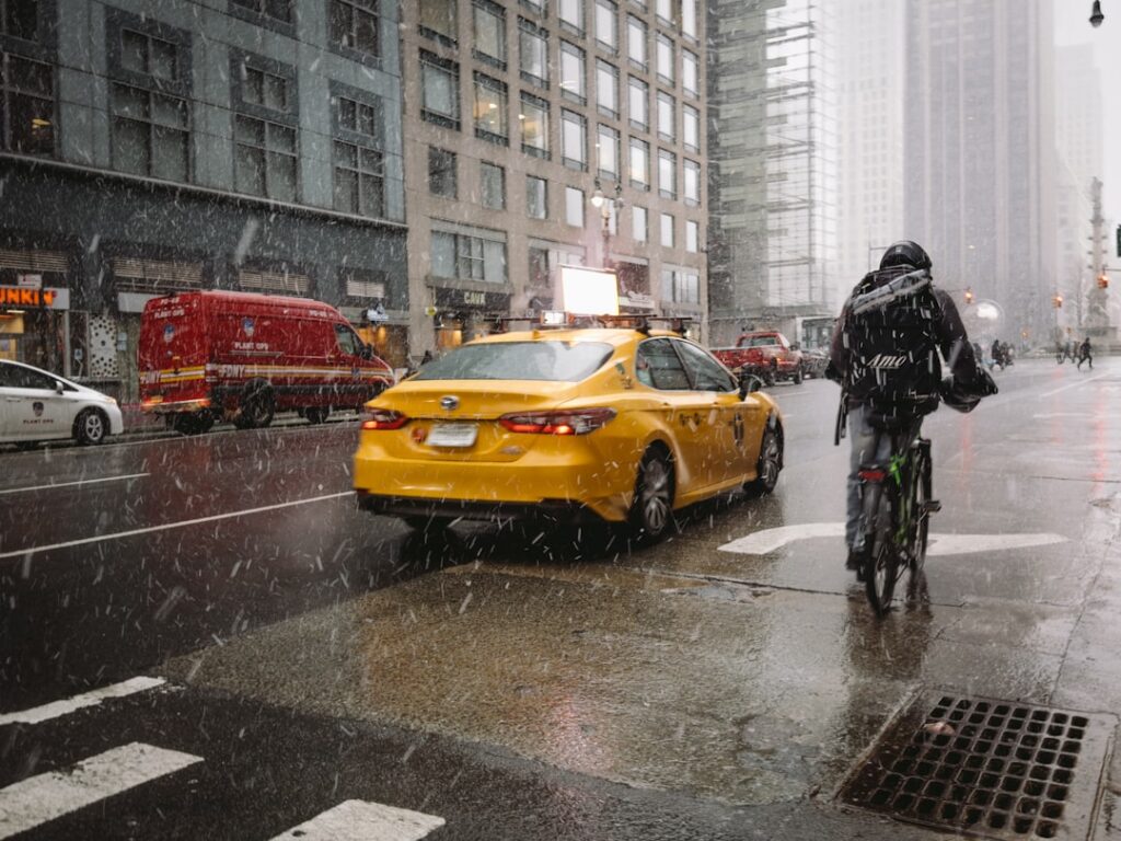 Yellow taxi and cyclist in snowy city street