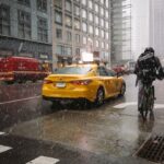 Yellow taxi and cyclist in snowy city street