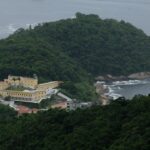 a large yellow building sitting on top of a lush green hillside