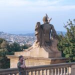 Man singing near statue overlooking city skyline