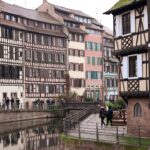 Colorful half-timbered houses line a canal with reflections.