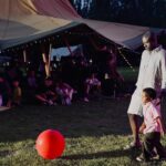 Man and child near red ball at outdoor event