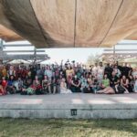 A diverse group of men and women posing outdoors under a wooden structure in Orlando, FL.