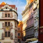 Charming street view of historic architecture in Prague city center, showcasing ornate facades in golden sunlight.