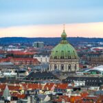 Stunning aerial view of Frederik's Church and Copenhagen skyline at sunset with iconic architecture.