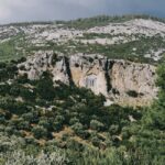 Historic ruins embedded in rocky landscape surrounded by lush greenery and hills.