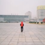 Person walks toward building in a foggy cityscape.