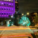 City street at night with purple illuminated building.